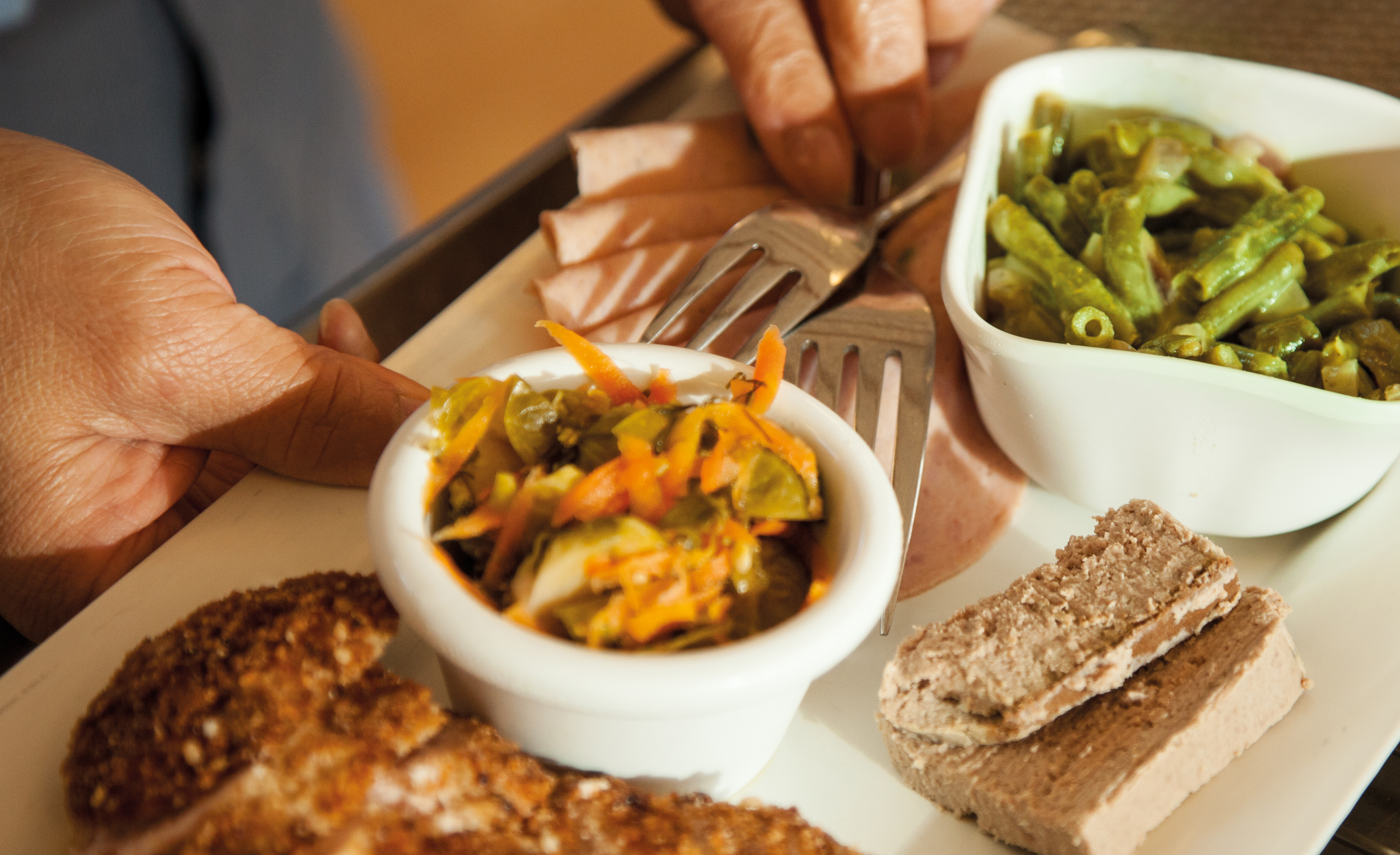 Mad på etn tallerken. Der er blandt andet grønne bønner, kødpålæg, leverpostej og brød på tallerkenen.